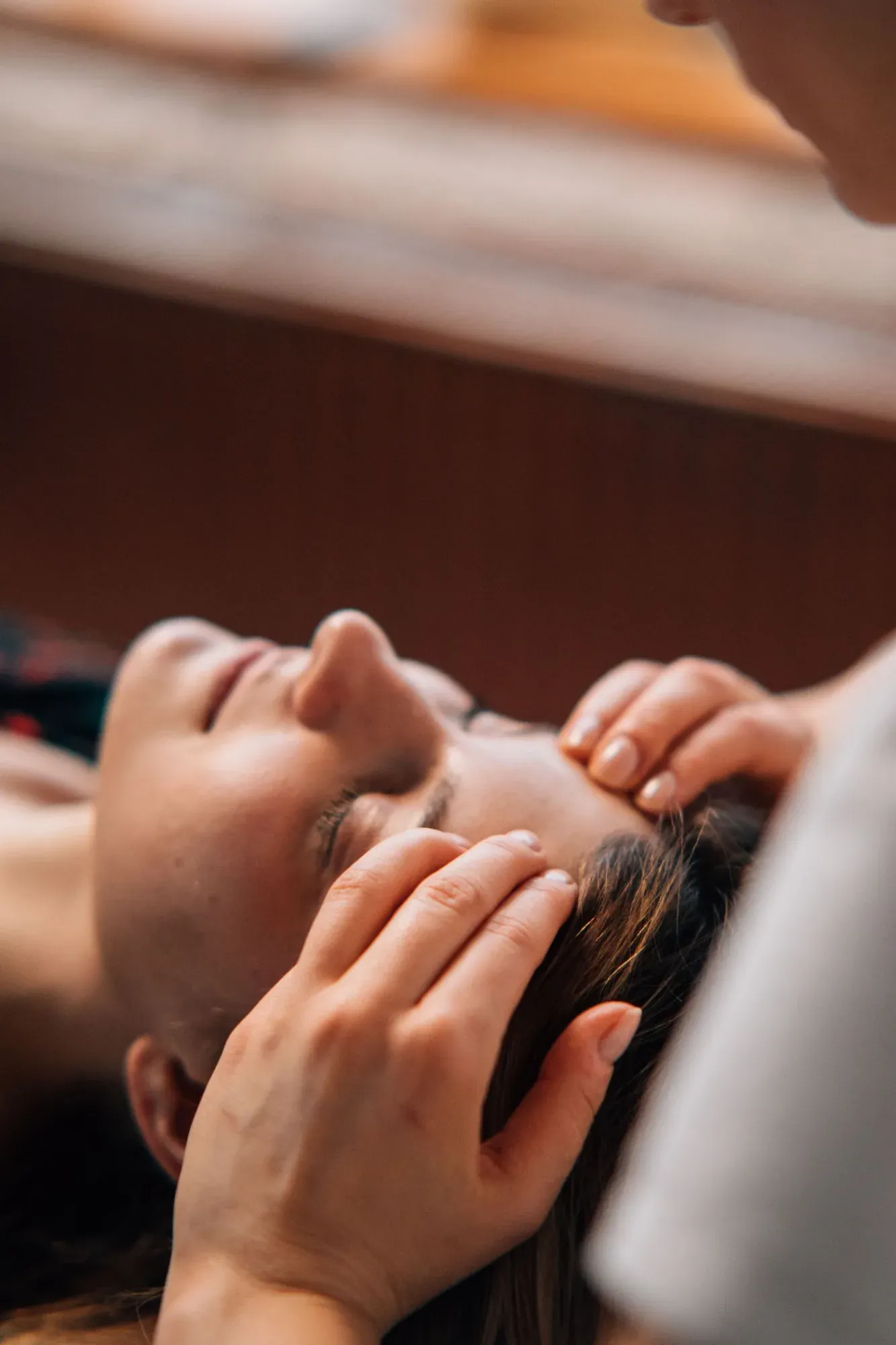 Des doigts posés en douceur sur le front d’une personne allongée, les yeux fermés